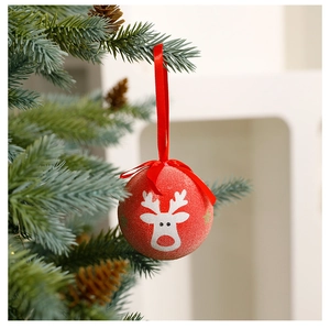 Detail of red Christmas ball with white reindeer pattern hanging on a festive tree branch