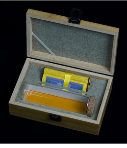 Detailed view of luxury wooden gift box with linen lining, scroll, and glass tube inside
