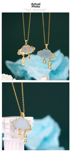 Close-up of golden cloud necklace with blue pendant, raindrop charms, and cubic zirconia