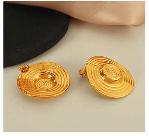 Macro view of gold round earrings with textured concentric circles and stud closure