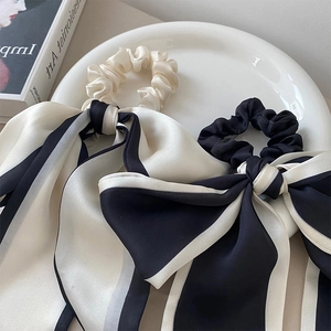 Dettaglio di elastici a fiocco in raso di seta a righe e beige su vassoio ceramico