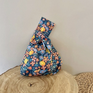 Detail of floral canvas wrist bag with lemon print on rustic wood slice surface