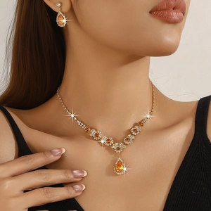 Detail of bridal jewelry set with sparkling orange pear-cut stones and gold necklace