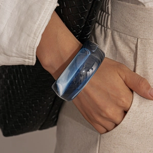 Detail of wide resin acrylic bangle with deep blue and white marble ink texture pattern
