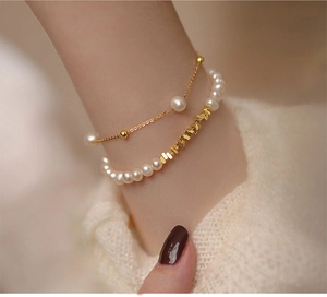 Detail view of double-layer bracelet with freshwater pearls and gold beads on wrist