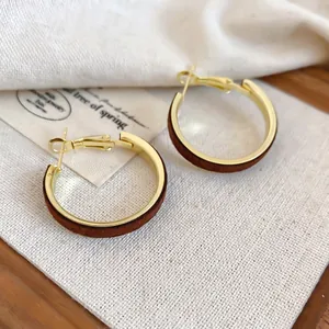 French vintage gold metal hoop earrings with brown velvet wrap on wooden base