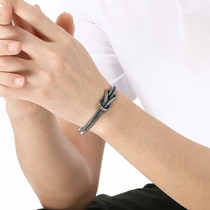Close-up of twisted knot silver bangle with industrial texture on a male wrist