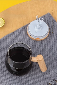 Close-up of glass stirring mug with wood handle and 400ml scale on a rustic table