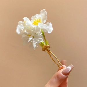 Gros plan d'un pic à cheveux élégant avec fleurs en tissu blanc et une fourche dorée