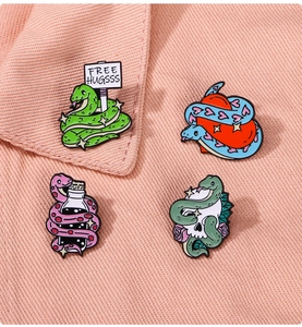 Macro shot of colorful snake enamel pins featuring skulls and hearts on pink denim fabric