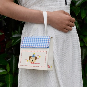 Cartoon gift bag with blue checkered pattern and ribbon handle shown in outdoor setting