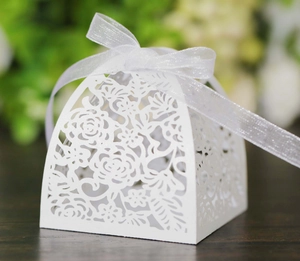 Detailed view of white laser-cut floral favor box with a white organza ribbon bow