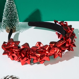 Dettaglio di un cerchietto natalizio con fiori regalo rossi lucidi su superficie bianca