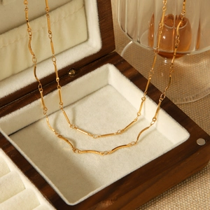 Détail d'une chaîne en acier inoxydable doré sur une boîte à bijoux en bois sombre