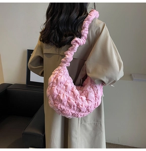 Close-up of pink quilted cloud bag with pleated strap worn by model in chic interior