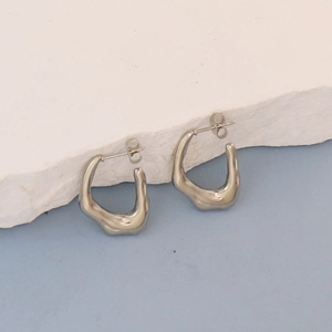 Detailed view of silver organic liquid-shaped oval earrings on white stone