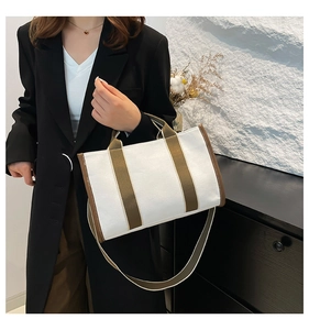 Detailed view of beige canvas tote bag with brown straps styled with a black blazer