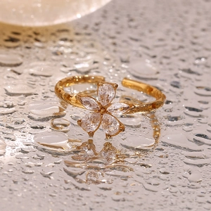 Macro shot of gold floral open ring with clear zircons on water drops surface