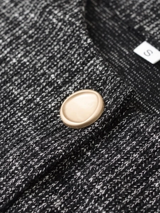 Dettaglio in tessuto tweed bianco e nero con bottone dorato ed etichetta taglia S