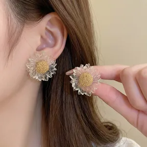 Elegant transparent flower stud earrings with golden textured centers on model