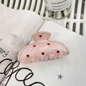Pince à cheveux cœur rose en acrylique avec gemmes rouges et cristaux sur magazine