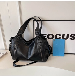 Close-up of black PU leather tote bag showing metallic zipper and rivet details