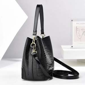 Macro detail of crocodile texture bucket bag with shiny leather trim and gold hardware