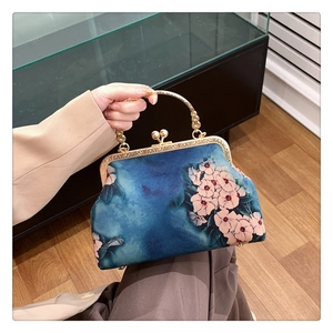 Detail of vintage blue floral fabric on a handbag with elegant gold metal frame clasp