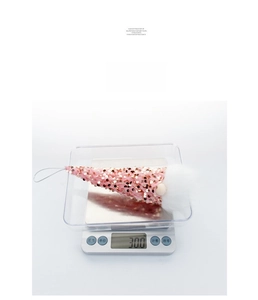 Close-up of a pink sequined Christmas gnome ornament weighing 30g on a digital scale