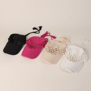 Flat lay of handmade crochet sun hats in black, rose, beige, and white with tassels