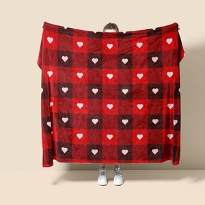 Detail of red and black buffalo plaid flannel blanket with white heart prints