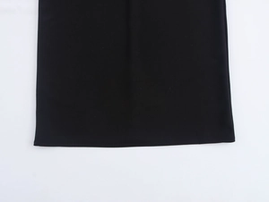 Détail de l'ourlet de la robe en maille noire montrant les coutures et la texture du tissu