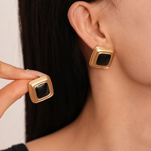 Vintage gold square stud earrings with black enamel inlay shown on female model