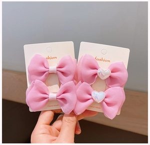 Close-up of pink organza bow hair clips with heart pearls on a display card