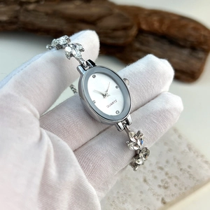 Detail view of silver oval quartz watch featuring crystal-embellished metal strap