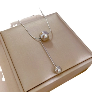 Minimalist titanium steel tassel necklace with silver beads on a beige display cushion
