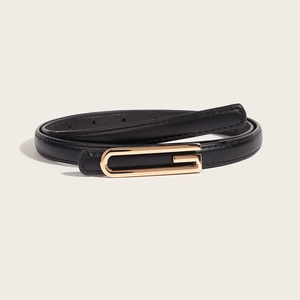 Minimalist black leather belt with gold U-shaped buckle for jeans on a beige background