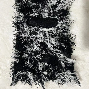 Detail of black and white knitted balaclava showing distressed fringe and woven texture