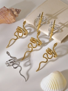 Dettaglio di anelli a forma di serpente oro e argento e gioielli geometrici moderni