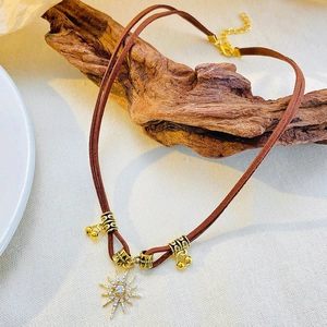 Detail of Bohemian leather necklace featuring a sunburst pendant with sparkling rhinestones