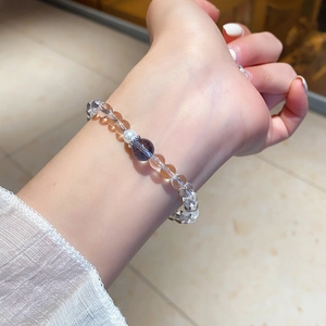 Détail du bracelet en cristal blanc et pierre violette porté au poignet d'une femme
