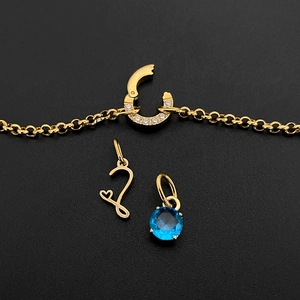 Detailed view of gold DIY jewelry charms featuring heart 'L' initial and blue gemstone.