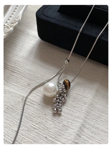 Detailed macro view of the silver snake chain and brown tiger eye pearl pendant necklace