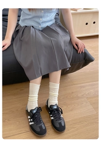 Detailed view of beige lace mesh calf socks styled with pleated skirt and casual shoes
