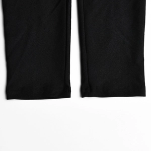 Détail des coutures noires et de la texture du tissu sur le bas du pantalon