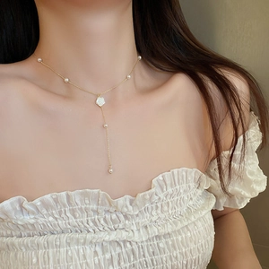 Détail du collier en Y doré avec un pendentif rose blanche et petites perles