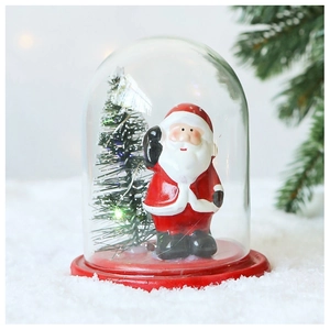 Close-up of lighted Christmas snow globe with Santa Claus and a mini LED tree inside