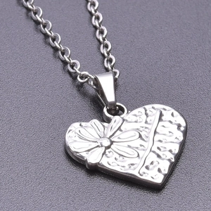 Vue macro d'un pendentif cœur en acier inoxydable avec gravure de marguerites détaillée