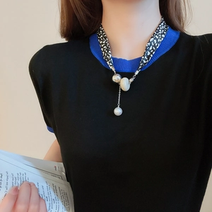 Gros plan sur le collier foulard en soie léopard avec perles et pendentif perle
