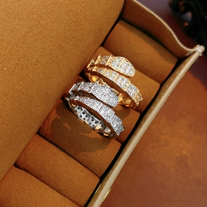 Close-up of gold and silver snake rings with zircon stones in a jewelry box